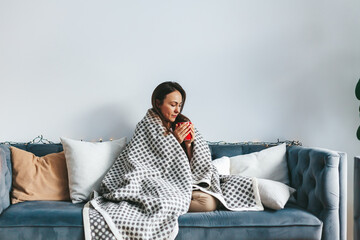 Woman on the couch savoring a warm drink under her cozy blanket