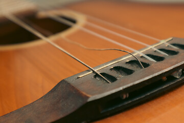 Classical guitar with broken string. Closeup of classical acoustic wooden guitar with a broken string.