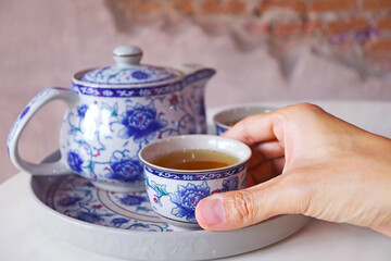 Closeup of Hand Holding a Cup of Hot Chinese Oolong Tea