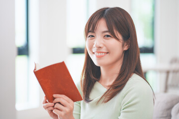 リビングのソファに座って読書する女性