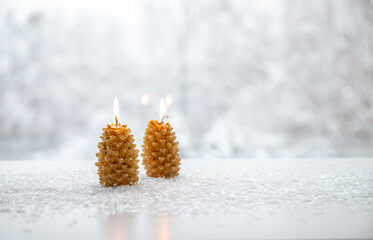 Spruce tree shape candles burning on white snowy background with winter landscape. Lot of copy...