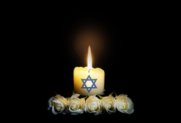 White roses with a burning candle on the dark background with Israeli flag. Funeral flower and...