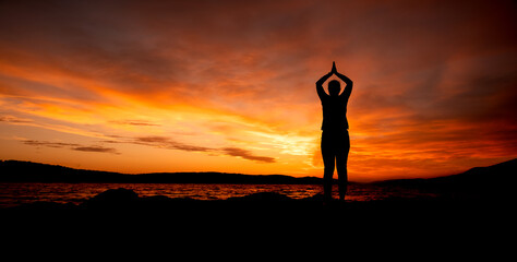 Kobieta ćwicząca joge na plaży na tle zachodu słońca, woman practicing yoga - obrazy, fototapety, plakaty
