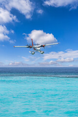 Fototapeta na wymiar Exotic seascape seaplane on Maldives sea landing. Vacation or holiday luxury travel transportation in tropical popular destinations. Airplane flight and landing on calm ocean bay