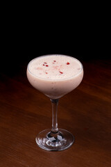 red fruit syrup with spoon in glass of creamy baileys milk liqueur cocktail on wooden table and background top view