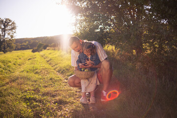 Little beautiful girl with her dad eating apples from a wicker basket in a sun-drenched meadow...