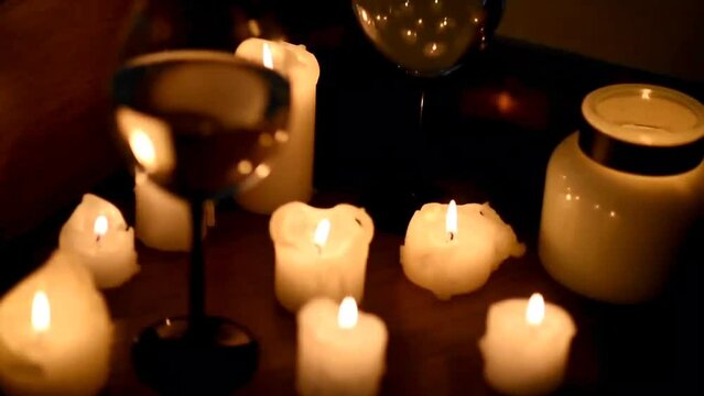 glass of wine and candles in the dark. The focus shifts from the glass to the candles and the image is blurred in the side. Romantic dinner