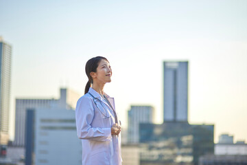 ビジネス街の町並みと白衣を着た日本人の女性医師
