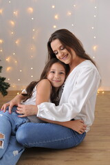 mãe e filha juntas e felizes em demonstração de carinho amor e afeto em frente a arvore natalina 