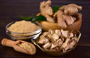 Fresh ginger root, dried ginger and ginger powder on a dark wooden background.