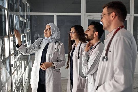 A group of doctors discusses the diagnosis of X-rays in the office. Fracture of the leg and hip joint. In the background, an Arabian professor explains to students physicians anatomy