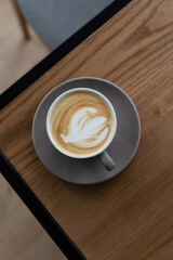 Coffee in cup on wooden table in cafe with lighting background