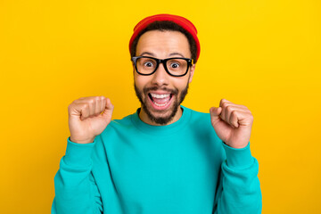 Naklejka premium Photo of impressed man wear teal sweatshirt red beanie hat scream yeah clenching fists win lottery isolated on yellow color background