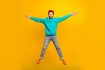 Fototapeta na wymiar Full size photo of satisfied optimistic guy dressed red hat denim trousers flying in star pose isolated on yellow color background