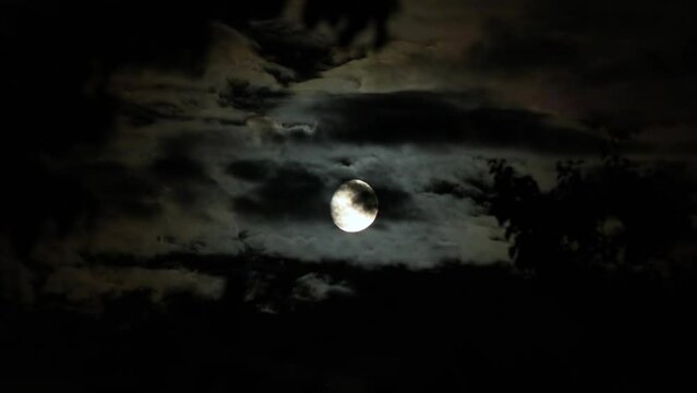 Halloween night - Spooky Moon on a dark cloudy night with clouds flying in front of Moon like in thrillers and horror movies. Real shooting dark sky, black clouds