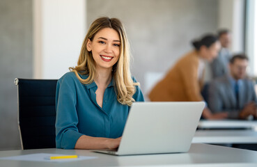 Successful young attractive businesswoman working on laptop in her workstation at office