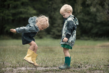 Kids playing on meadow in raincoats after raining
