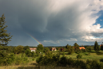 rainbow over the village, cloudy skies, dark blue color