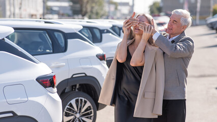 An elderly Caucasian man gives a new car to his beloved woman.