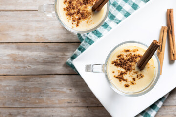 Homemade eggnog with cinnamon on wooden table. Typical Christmas dessert.  Top view. Copy space