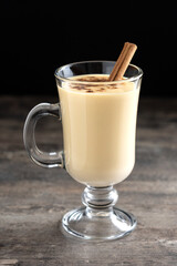Homemade eggnog with cinnamon on wooden table. Typical Christmas dessert. 