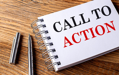 CALL TO ACTION text on notebook with pen on wooden background