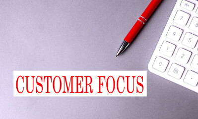 CUSTOMER FOCUS text written on a gray background with pen and calculator