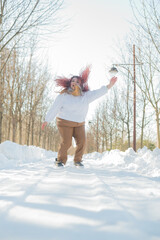 Smiling plump redhead woman jumping in park in winter. 