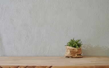 Vase of plant in front of the grey stone wall, wooden table style.
