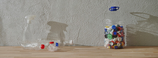 Caps inside plastic bottle, recycle, grey stone wall concept and wooden table.