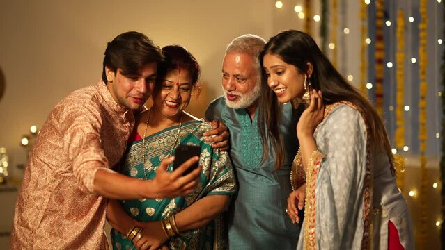 Indian family happily waving and chatting on a video call during Diwali celebrations, colourful decorations.a Hindu festival,diwali festival.standing toghter.