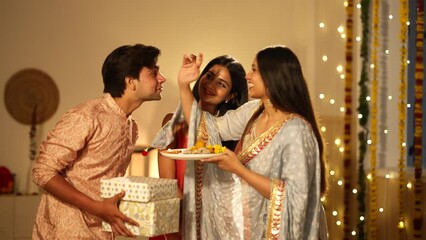Indian Woman giving puja blessings to her husband from aarti thali after Diwali prayers. Husband giving gift to wife.Indian couple in traditional dress during the festival.