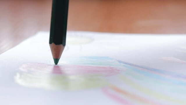 A child draws with a colored pencil in an album. Children's creativity, learning in kindergarten, school or at home. Pencil close up, selective focus. Color the picture