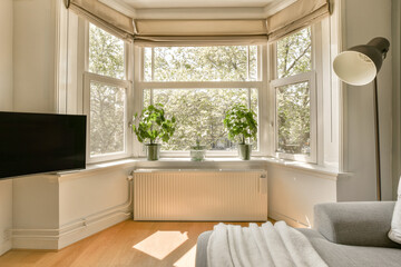 a living room with a large window and some plants on the windowsills in front of the tv screen