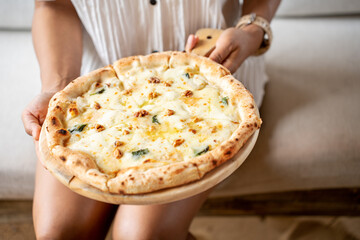woman holding Pizza quattro fromaggi on a wooden board. Four Cheese Pizza or Quattro Formaggi Pizza topped, gorgonzola on wooden background.