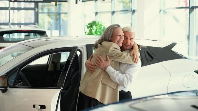 Mature Caucasian couple hugging with happiness while buying a new car. 