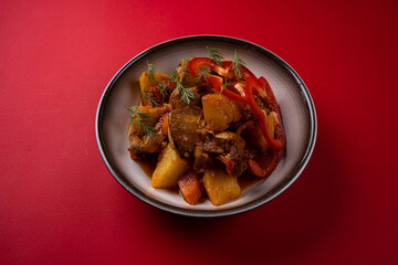 Boiled Potatoes with Meat on a Plate on a Red Background.