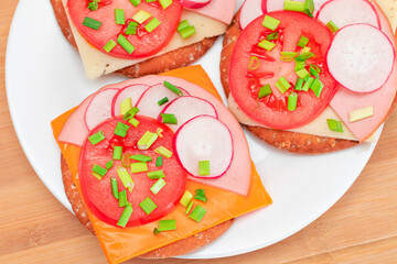 Crispy Cracker Sandwiches with Tomato, Sausage, Cheese, Green Onions and Radish on White Plate. Easy Breakfast. Quick and Healthy Sandwiches. Crispbread with Tasty Filling. Healthy Dietary Snack
