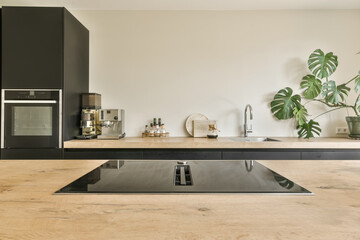 a modern kitchen with wood counter tops and black cabinets in the center of the room is a pot of plants
