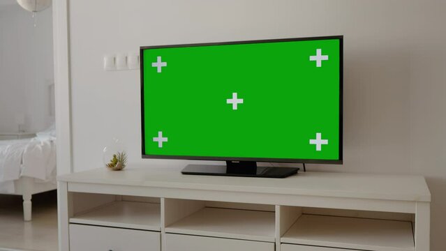 Chroma Key flat green screen tv monitor on stand in the living room. Background technology display mock up copy space television zoom in house office.