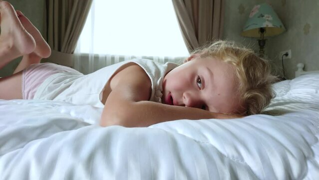 Little cute girl lying in the bed. Concept of awakening in the morning
