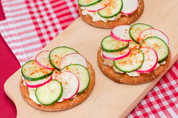 Light Breakfast or Diet Eating - Crispy Cracker Sandwich with Cream Cheese, Fresh Cucumber and Radish on Wooden Cooking Board on Magenta Background