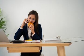 Busy and tired businesswoman eating Bread and milk for lunch at the Desk office and working to...