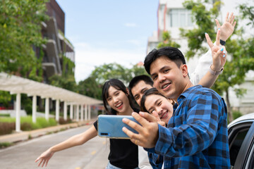 Fototapeta premium Group of happy young Asian students selfies and videos with smartphones together for vlog and social media on summer vacation. Concept of tourism and travel and road trip, friendship lifestyle.