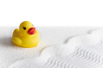 Yellow rubber duck on conceptual white sand in the form of water waves and beach white background