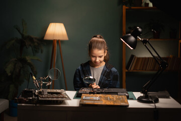 Caucasian teenage girl for searching way of fixing broken laptop. Cute child sitting at table and trying to repair laptop computer at home.