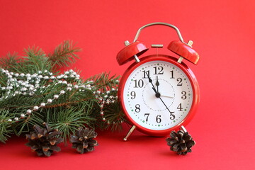 The red alarm clock is on a red background with Christmas decorations.