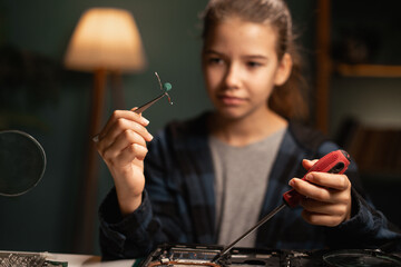 Children computer repair shop. Smart schoolgirl performing laptop maintenance. Child DIY fixing electronic components.
