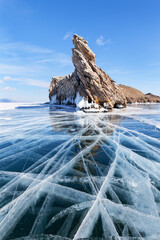 Sunny winter day on frozen Lake Baikal. Beautiful clear blue ice with cracks near Dragon Cape of...