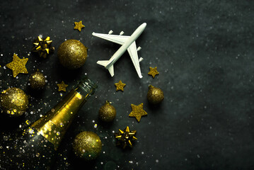 Christmas concept background. Champagne bottle,christmas balls,sparkling glitter and plane with space for text. Christmas travel concept
